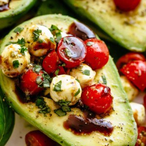 Basil Pesto Caprese Stuffed Avocado drizzled with balsamic glaze make an incredible light lunch or snack! Take creamy avocados to a different level! Sweet and juicy grape/cherry tomatoes with fresh mozzarella balls are tossed through basil pesto and spooned into avocado halves!