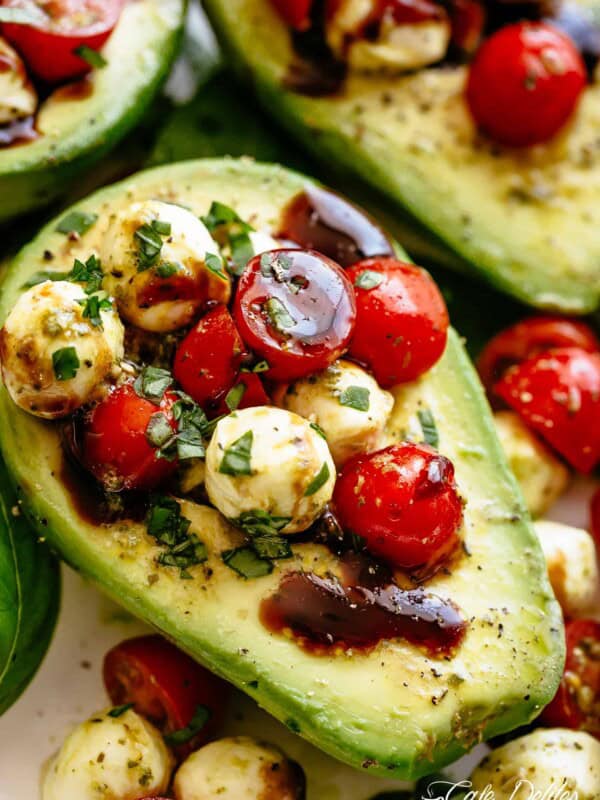 Basil Pesto Caprese Stuffed Avocado drizzled with balsamic glaze make an incredible light lunch or snack! Take creamy avocados to a different level! Sweet and juicy grape/cherry tomatoes with fresh mozzarella balls are tossed through basil pesto and spooned into avocado halves!