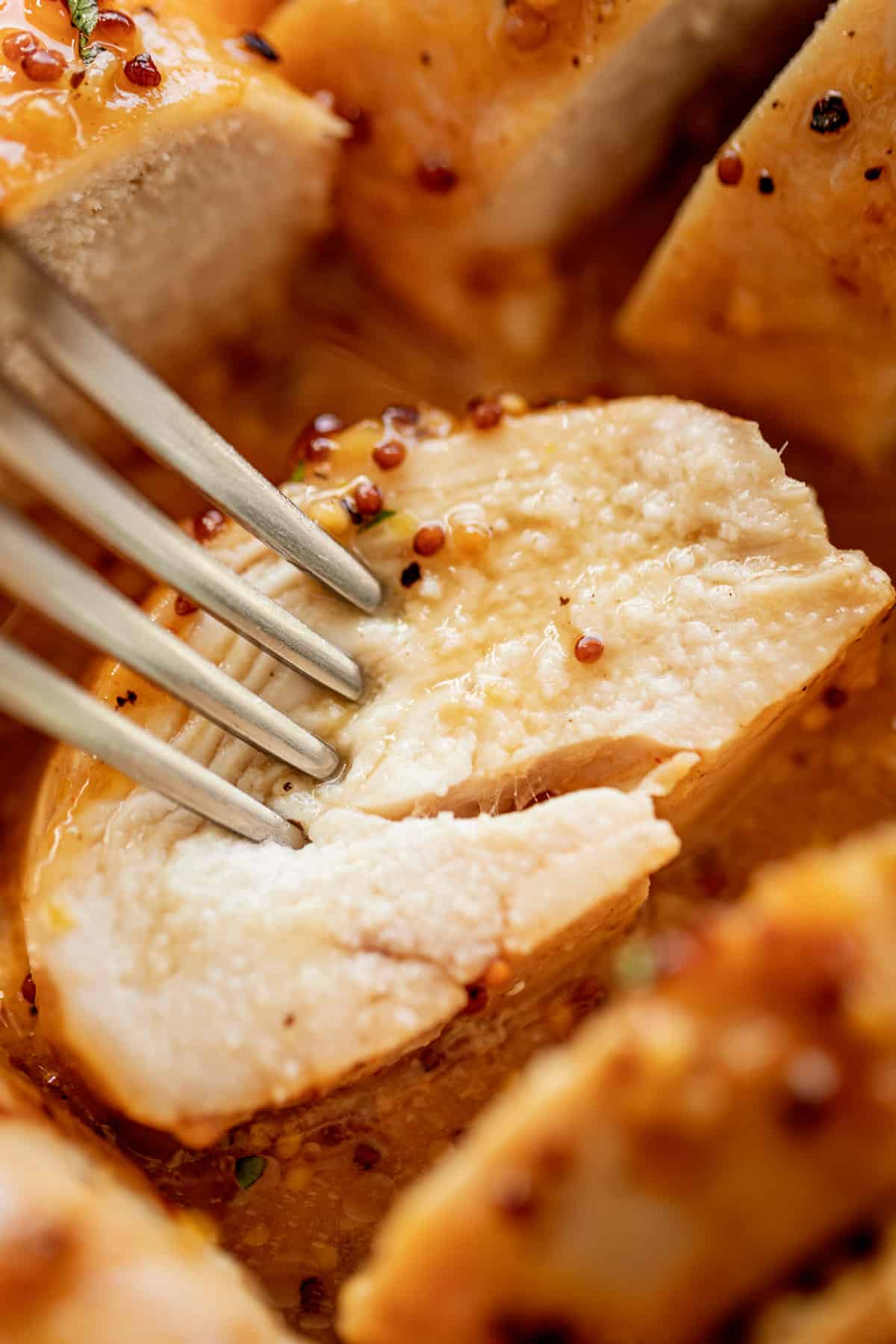 A slice of tender and juicy Baked Chicken Breasts with a delicious honey mustard sauce.