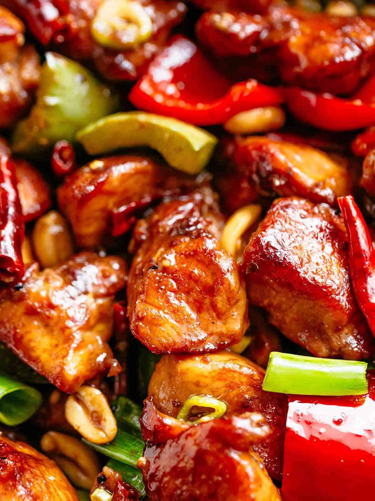Kung Pao chicken recipe! | cafedelites.com Close up image of Kung Pao Chicken in a sticky Kung Pao sauce with green and red chopped vegetables picked in with chicken pieces.