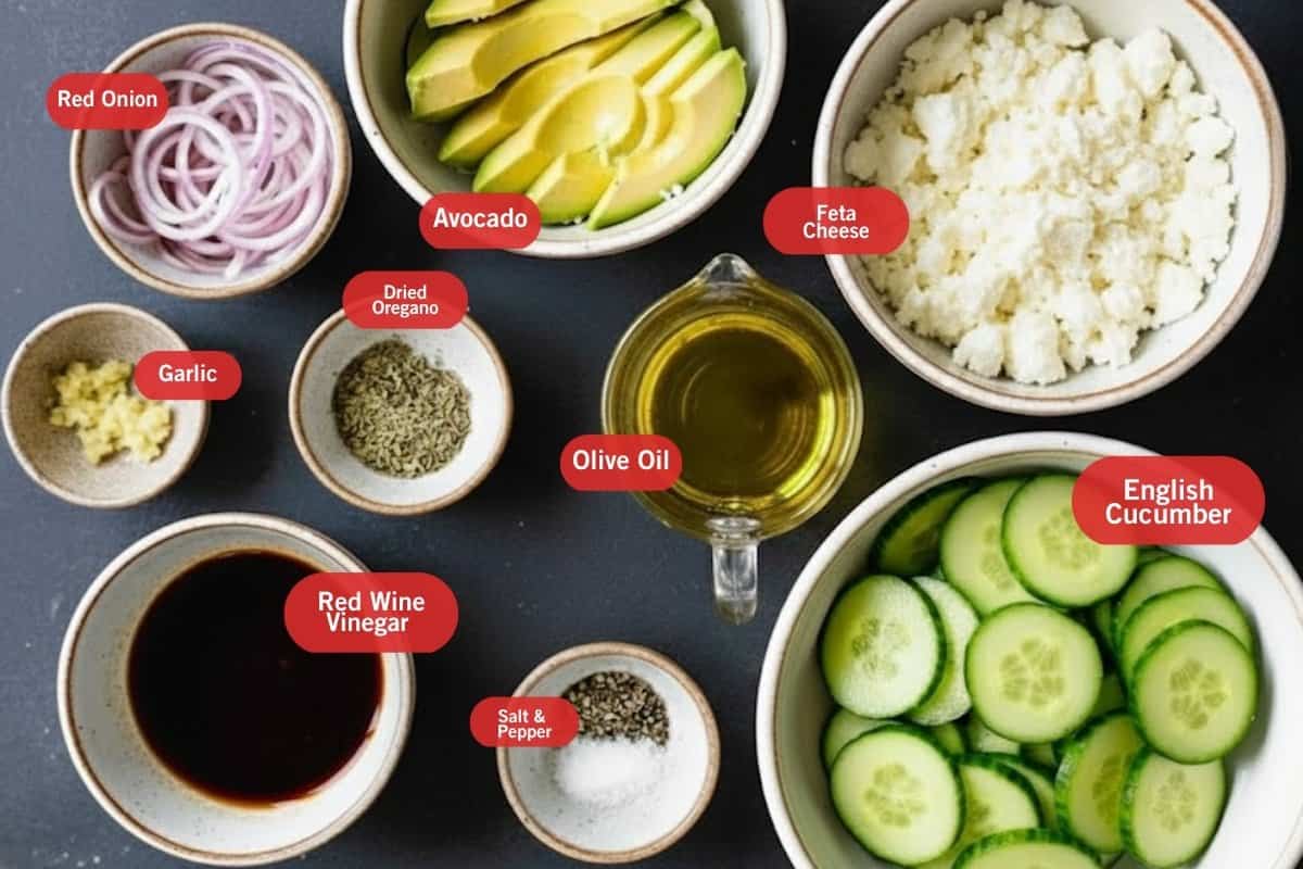 Flat lay photo of ingredient shot of red onion, avocado, feta cheese, garlic, olive oil dried oregano, olive oil, English cucumber, salt and pepper, red wine vinegar,