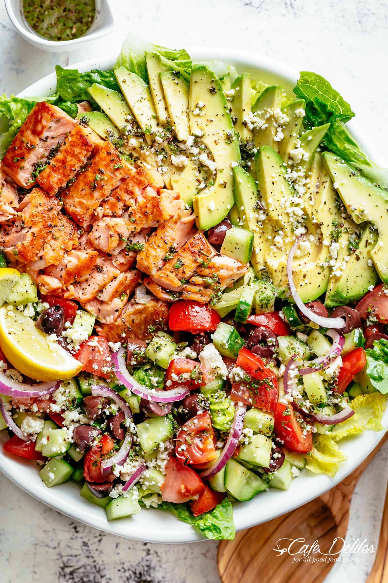 Avocado Salmon Salad with an incredible lemon herb Mediterranean dressing! Loaded with cucumber, olives, tomatoes and feta cheese on a plate