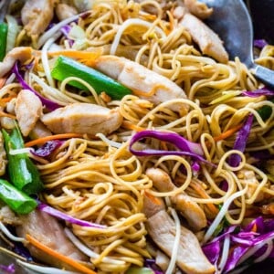 Wok spatula mixing chicken chow mein in a pan