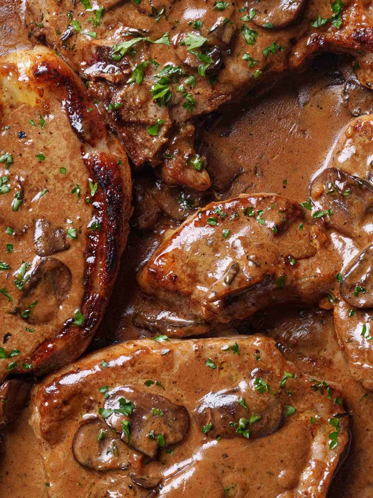 Seared Pork Chops with a creamy garlic mushroom sauce is a super easy dinner recipe! | cafedelites.com Golden-brown seared pork chops nestled in a pan of creamy garlic mushroom sauce.