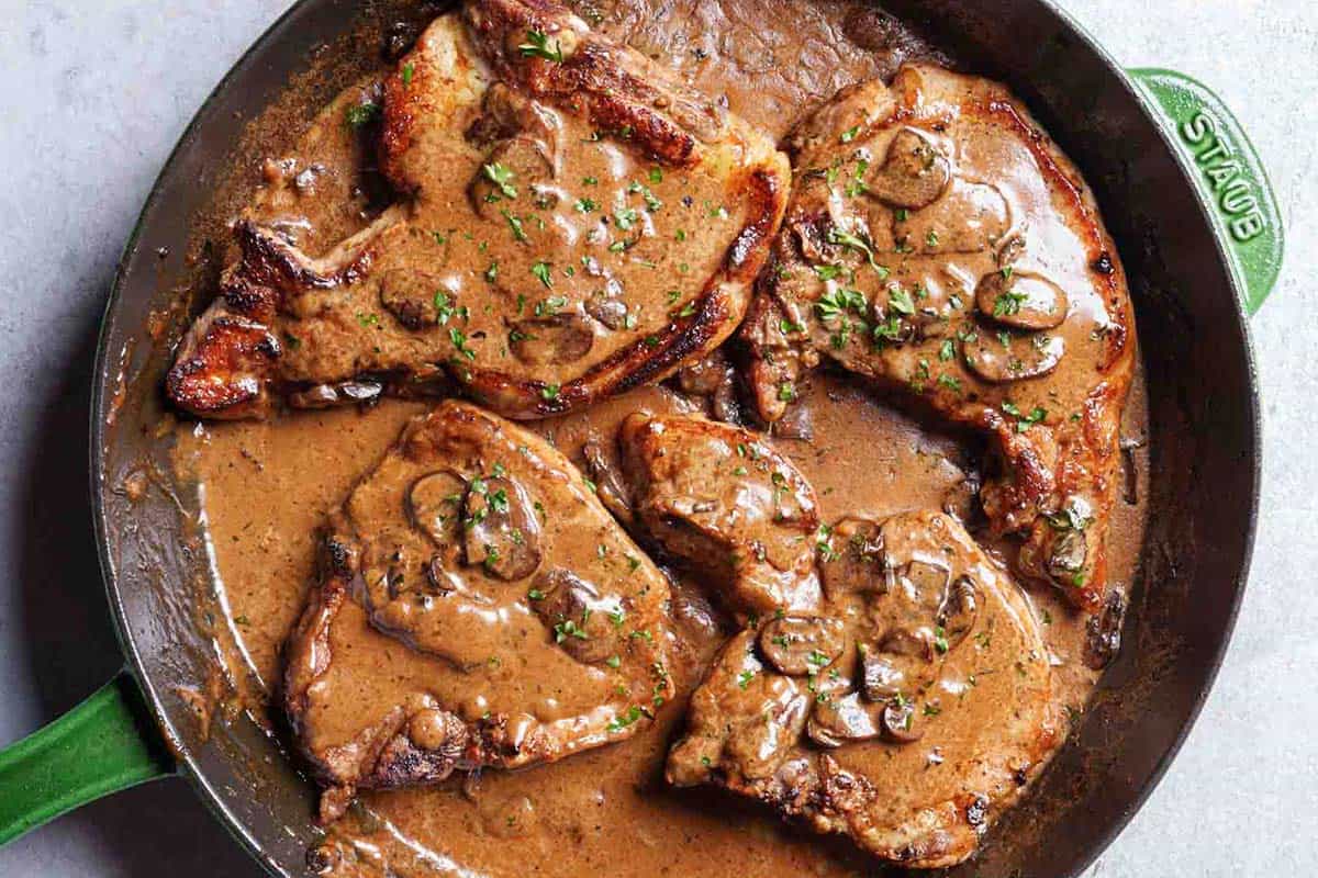 Top view of perfectly cooked pork chops nestled in a gentle, creamy sauce, ready to serve.