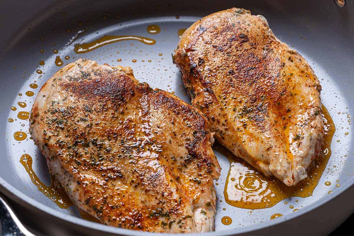 Chicken breasts sizzling in the pan, seared to a golden brown perfection and cooked through for tender, juicy bites.