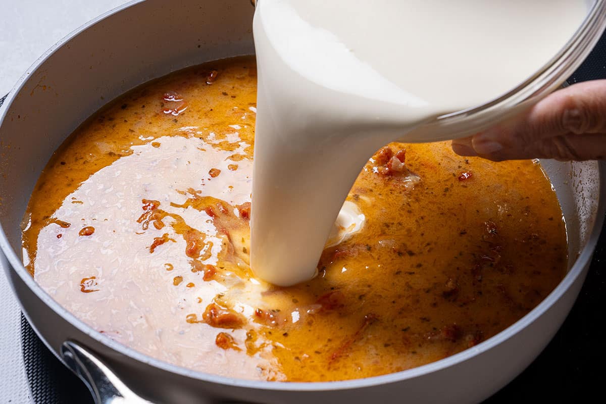Milk being poured into the pan to form the creamy sauce where the macaroni will cook to perfection.