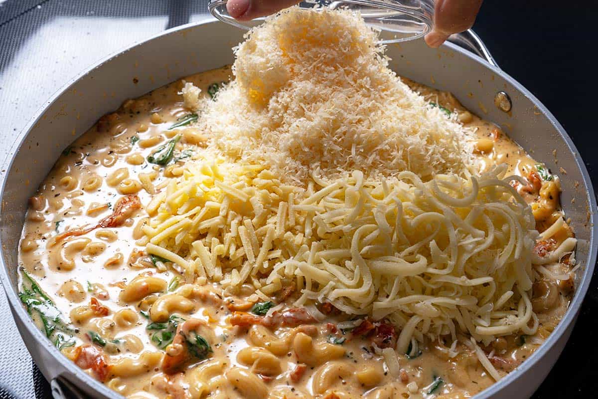 Cheese being stirred into the pot of macaroni and sauce, creating a creamy, luscious texture.