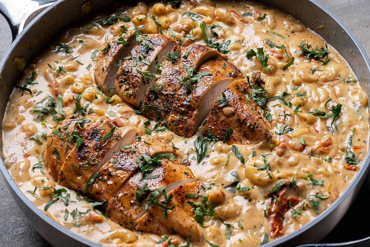 Sliced chicken mixed into the creamy macaroni and sauce, creating a hearty dish ready to be served.
