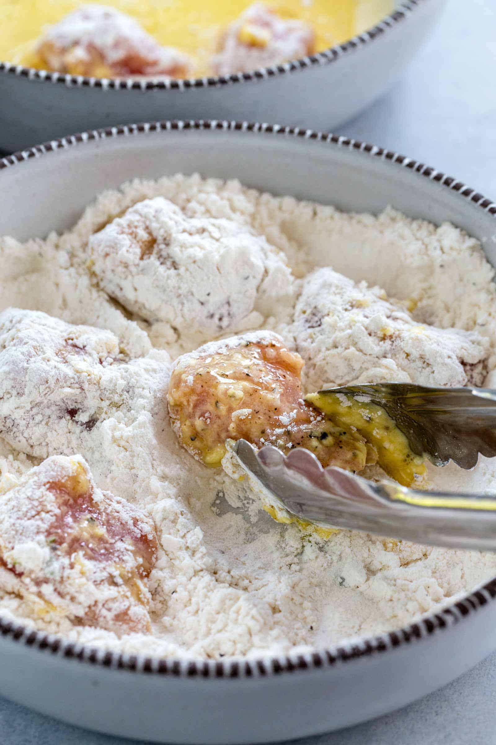 metal tongs coating pork into flour