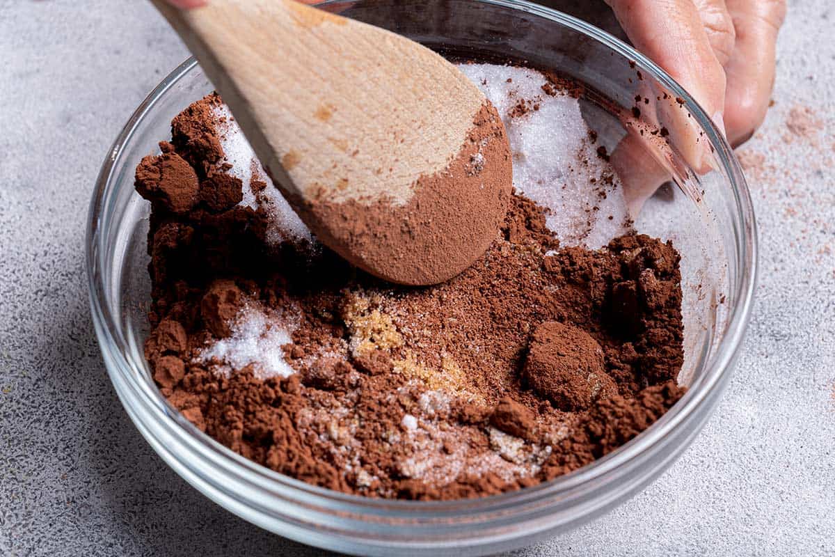 dry ingredients being mixed into a bowl close up white sugar, brown sugar and cocoa powder 