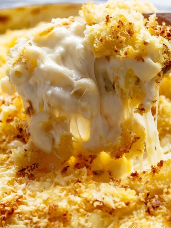 Cheesy and delectable Mac And Cheese being lifted by a spoon reveling stringing cheese