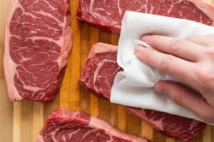 Patting the meat dry using paper towel.
