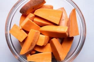 Sweet potatoes cut into large even chunks in a glass bowl.