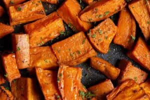 Finished roasted sweet potatoes with caramelised edges and chopped parsley.