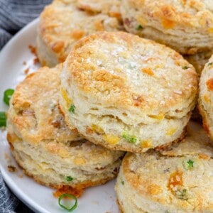 crunchy bacon cheddar biscuits stacked on a white plate