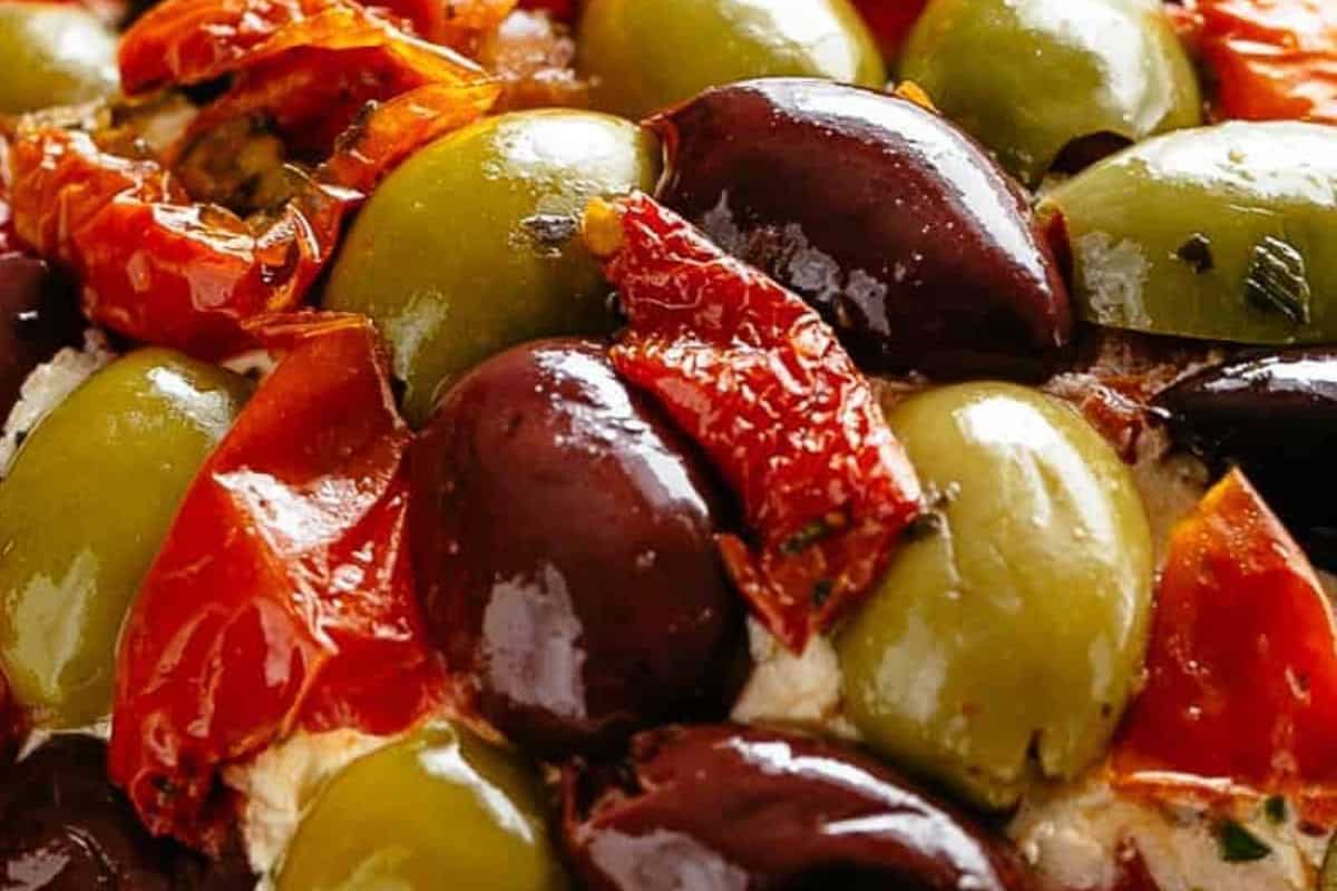 Lightly press the olives and tomatoes into the cheese ball until evenly coated.