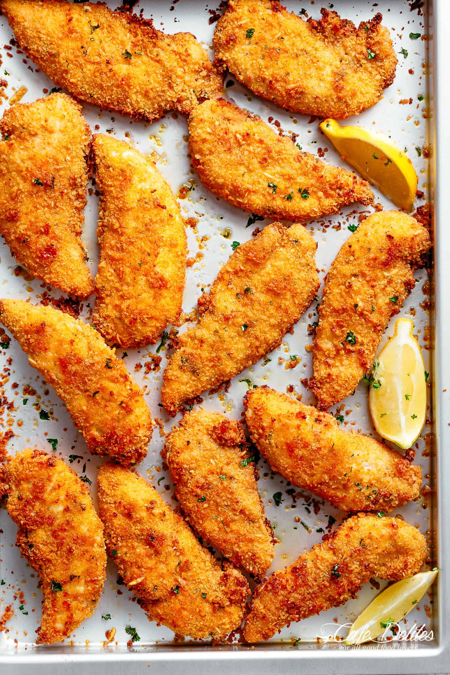 Crispy Oven Fried Baked Chicken Tenders | cafedelites.com Chicken Tenders on a baking pan with garlic, lemon and parmesan breading.