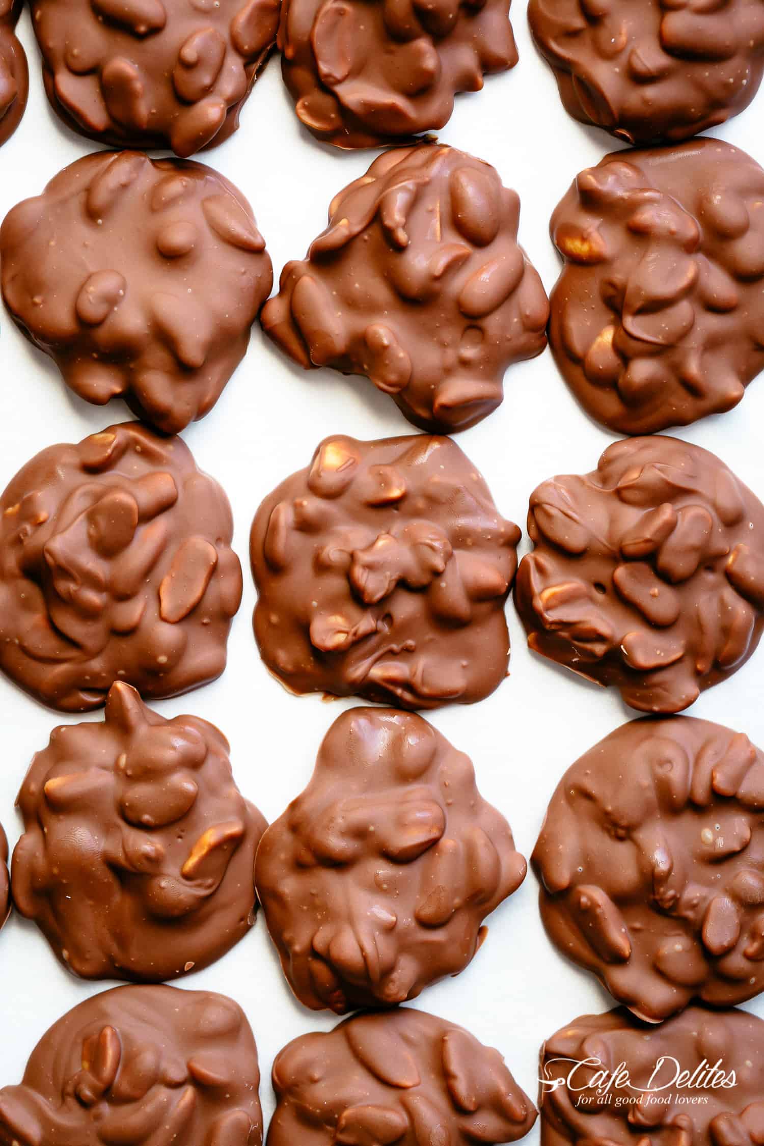 Chocolate Peanut Clusters with two melting methods and only a handful of ingredients! | cafedelites.com Chocolate Peanut Clusters on a baking sheet to cool down