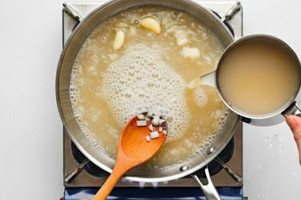 Add chicken broth to deglaze the pan and scrape any brown bits stuck on the surface of the pan.