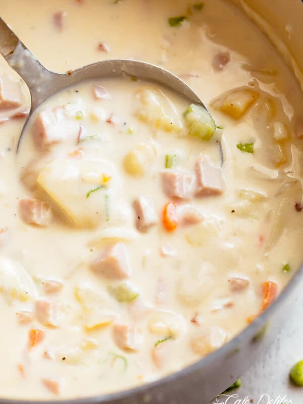 Creamy Ham And Potato Soup in a bowl being scooped up by a spoon before being eaten