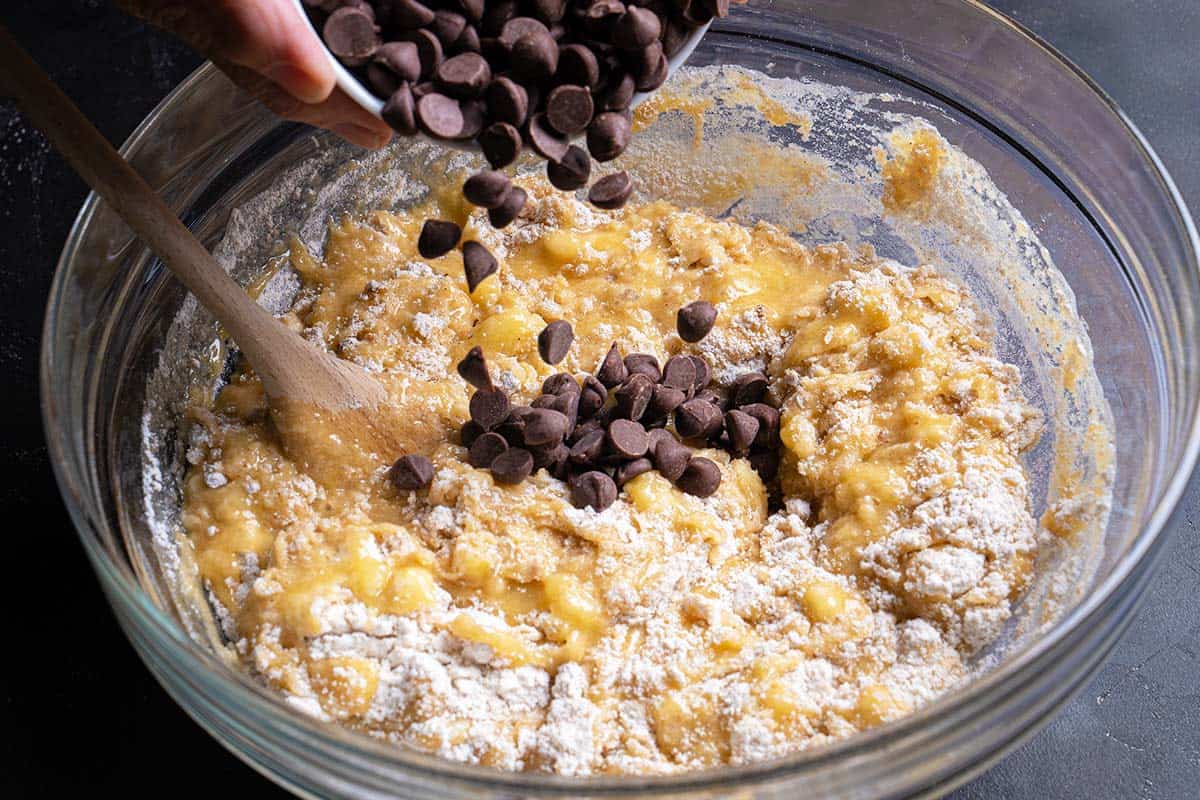chocolate chips being poured into batter mix