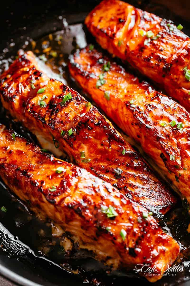 Close-up image of perfectly crispy salmon fillets coated in vibrant firecracker sauce.