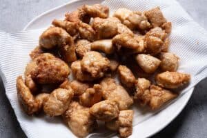 Crispy fried chicken pieces resting on a paper towel lined plate.