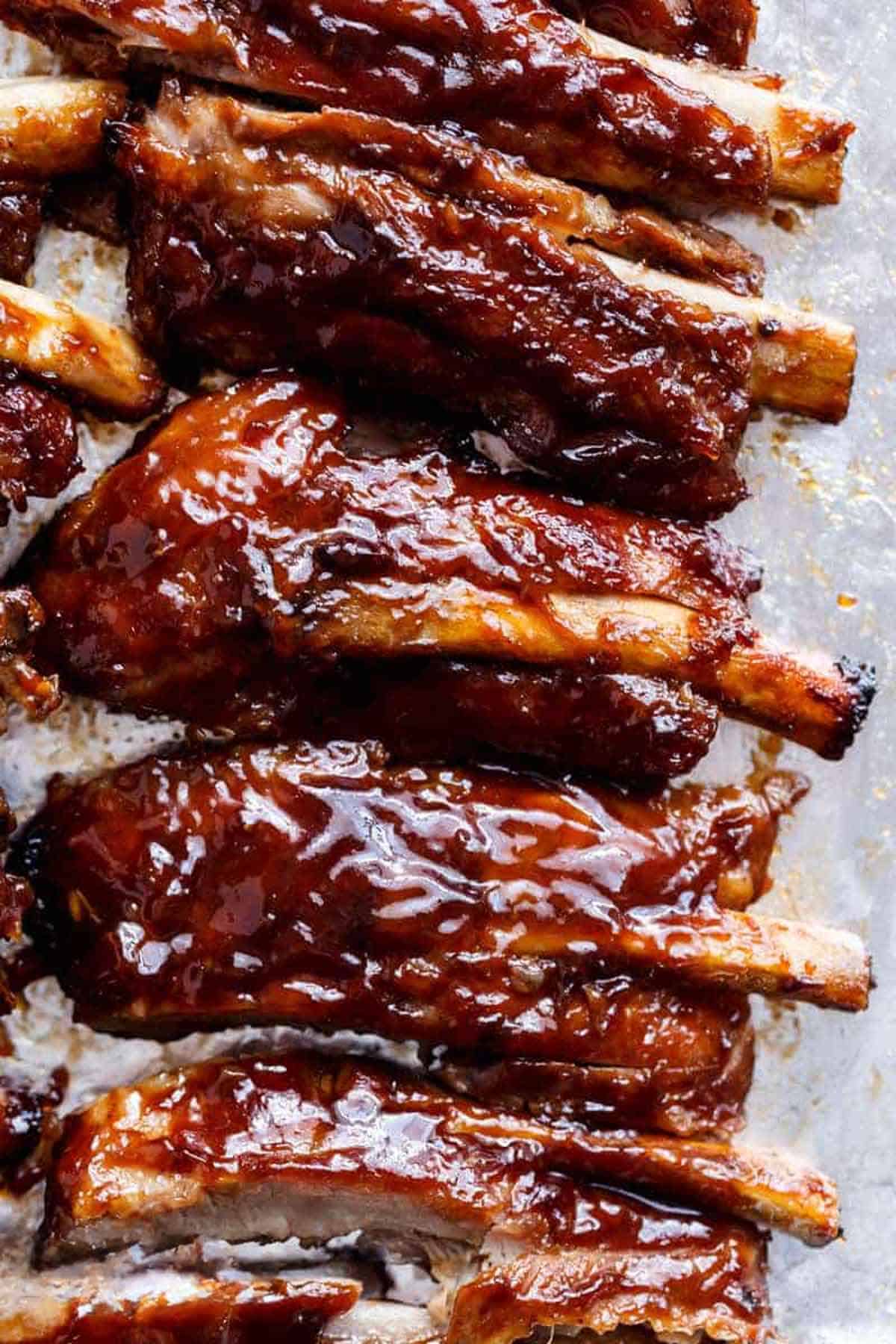 Close-up shot of perfectly cooked ribs dipped in barbecue sauce.