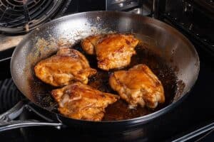 Thai satay chicken finishing cooking in an oven-proof skillet.