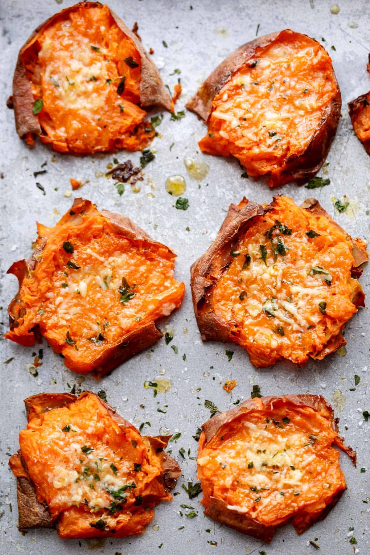 Pieces of Garlic Butter Smashed Sweet Potatoes With Parmesan kept on baking paper