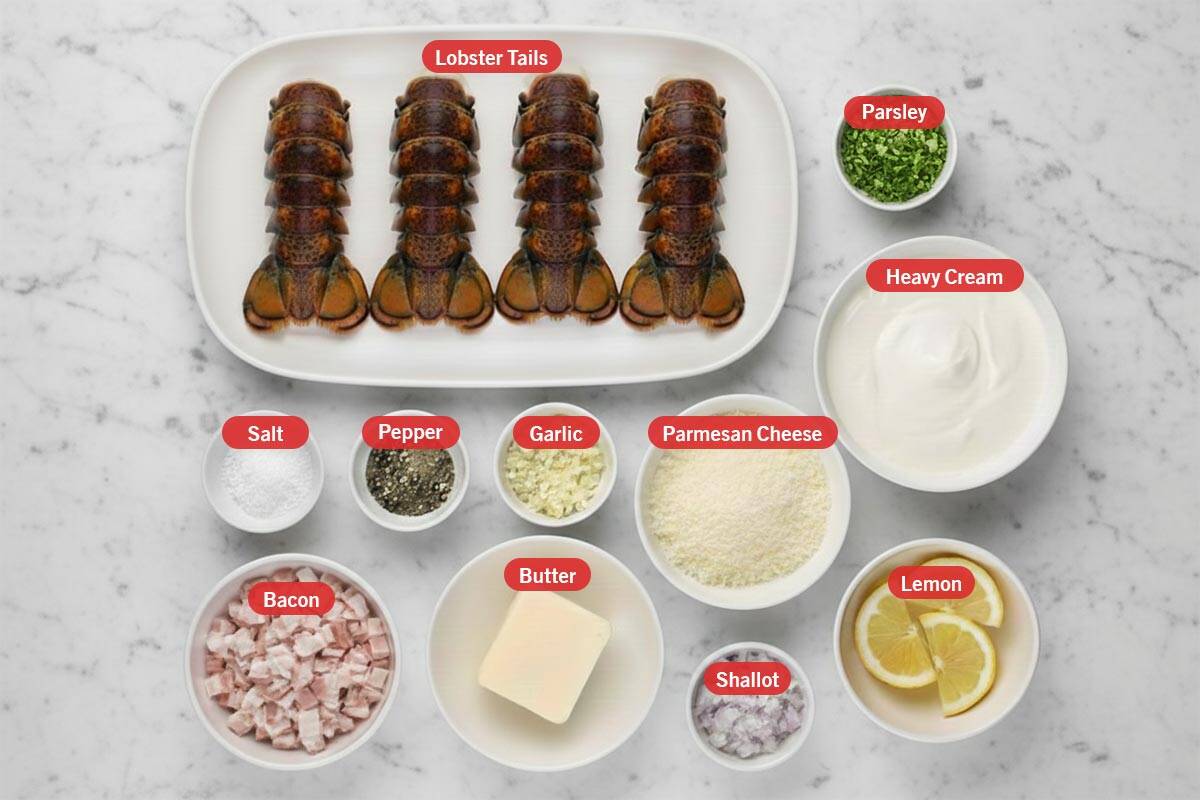 Top shot of ingredients: lobster tails, parsley, heavy cream, salt, pepper, garlic, parmesan cheese, bacon, butter, shallot, and lemon.