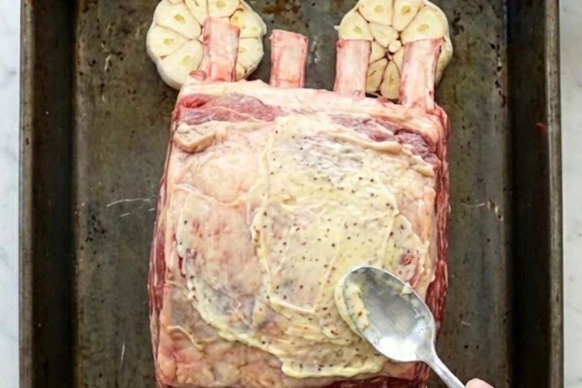 Arrange the garlic heads cut-side up in a roasting pan. Spread garlic butter on the bone side of the roast and place it on top of the garlic halves.