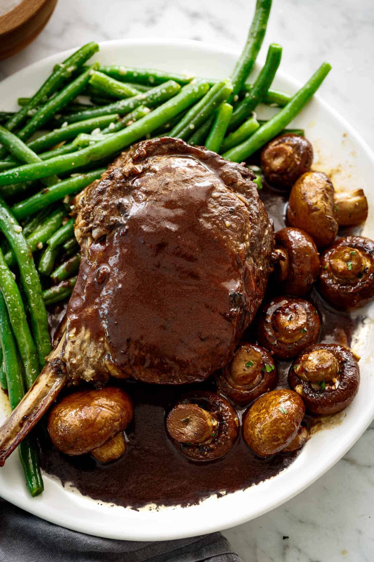 Enjoy Sautéed Buttery Green Beans plated as a side with a juicy prime rib and balsamic soy roasted mushrooms.