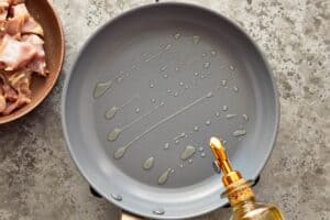 Olive oil heating in a skillet before browning chicken for slow cooker chicken corn chowder.