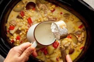 Milk and cornstarch being mixed into slow cooker chicken corn chowder to thicken the broth.