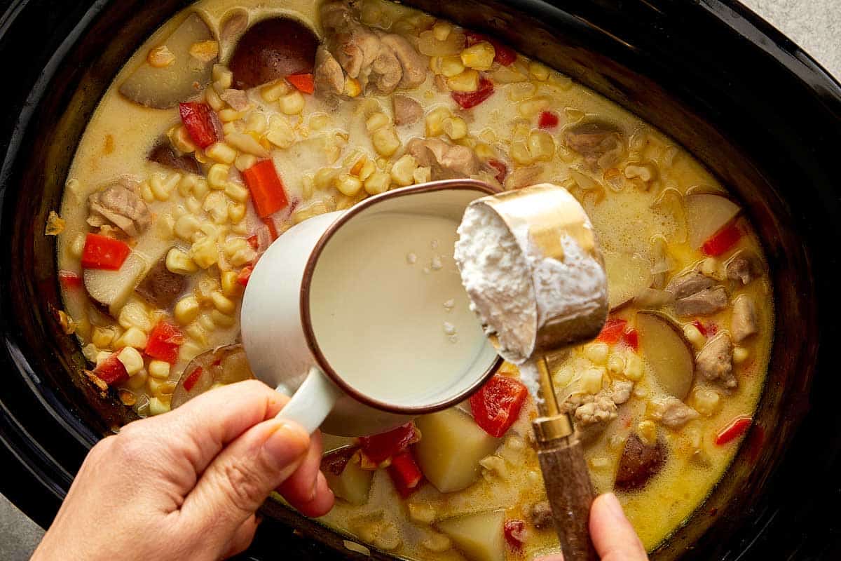 Milk and cornstarch being added to thicken slow cooker chicken corn chowder.