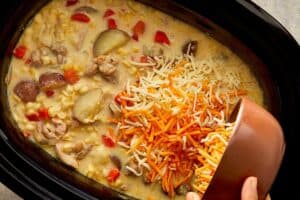 Cheddar and mozzarella cheese being stirred into creamy chicken bacon corn chowder.