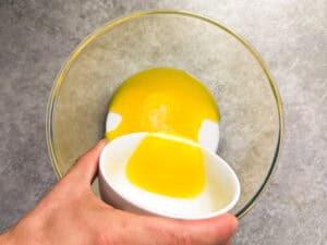 Pouring liquid butter in a glass with oil and sugar