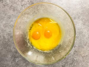Adding eggs to the mix of melted butter, oil and sugar