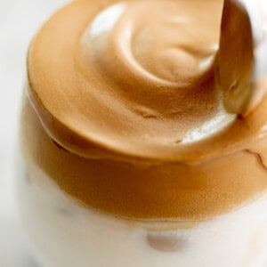 Whipped dalgona coffee on top of a glass full of milk.