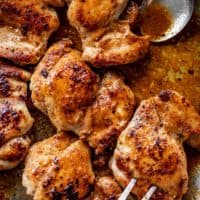 Crispy boneless chicken thighs in a silver pan, being picked up by a fork kitchen.