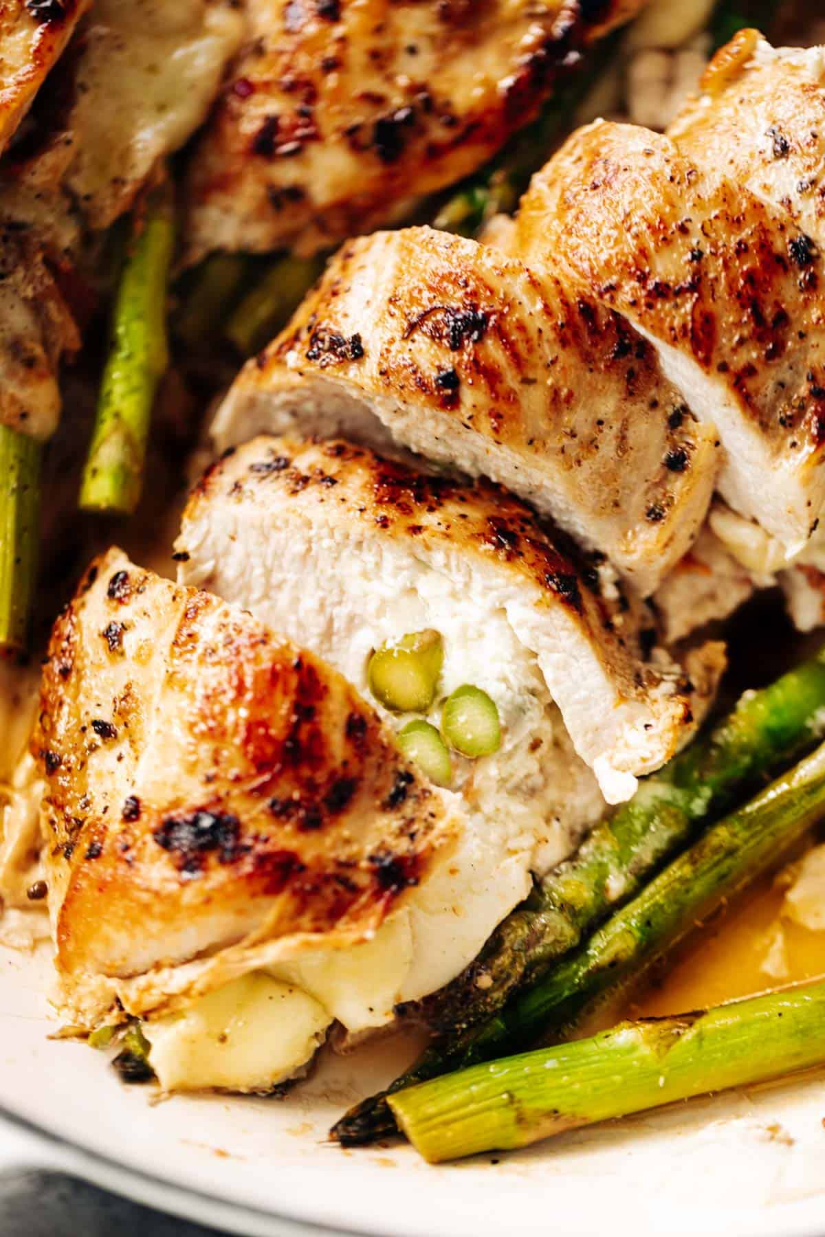 A close up image of one asparagus and mozzarella cheese stuffed in chicken breast sliced open to see the inside