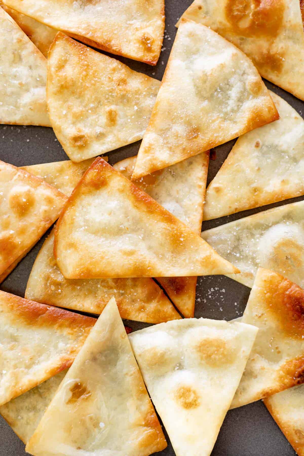 Crunchy Golden tortilla chips on a plate, sprinkled with salt.