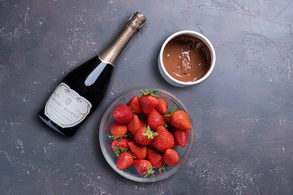 Image showing the essential ingredients for the recipe, including an alcoholic beverage of choice, chocolate, and fresh strawberries.