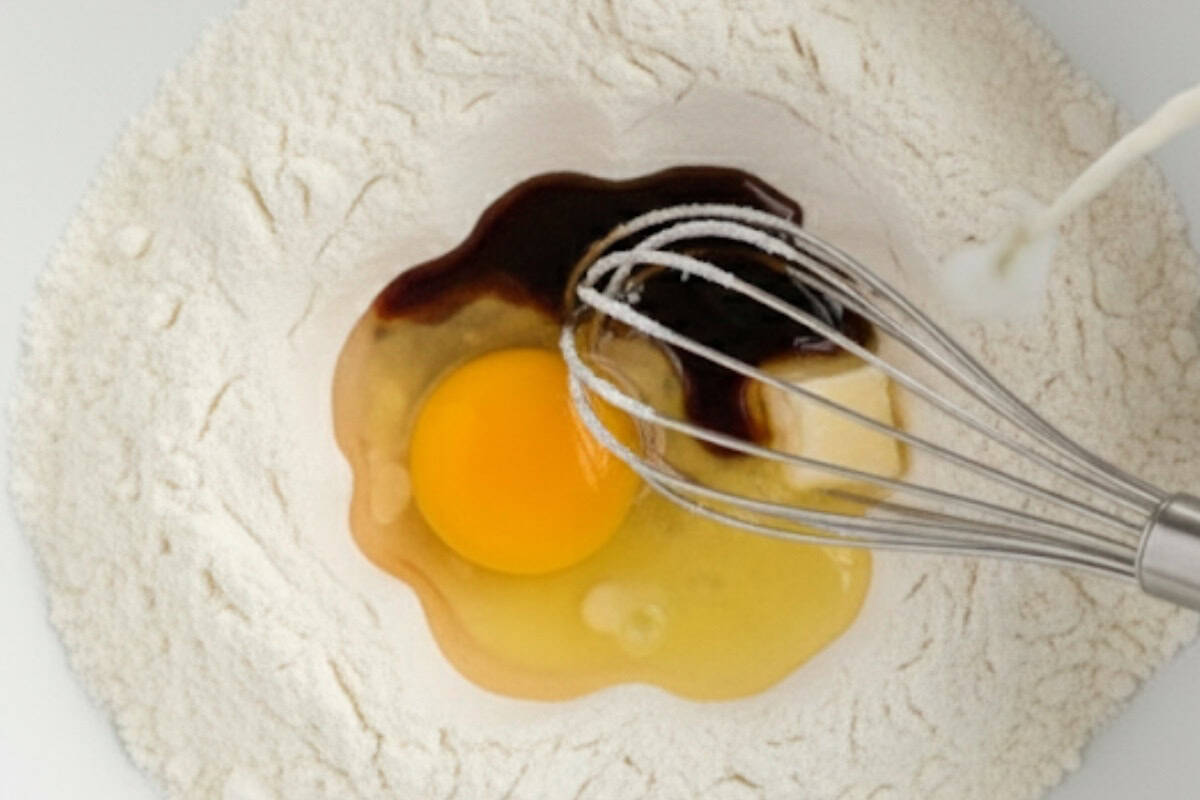 Pour in the milk, slightly cooled melted butter, vanilla, and egg.