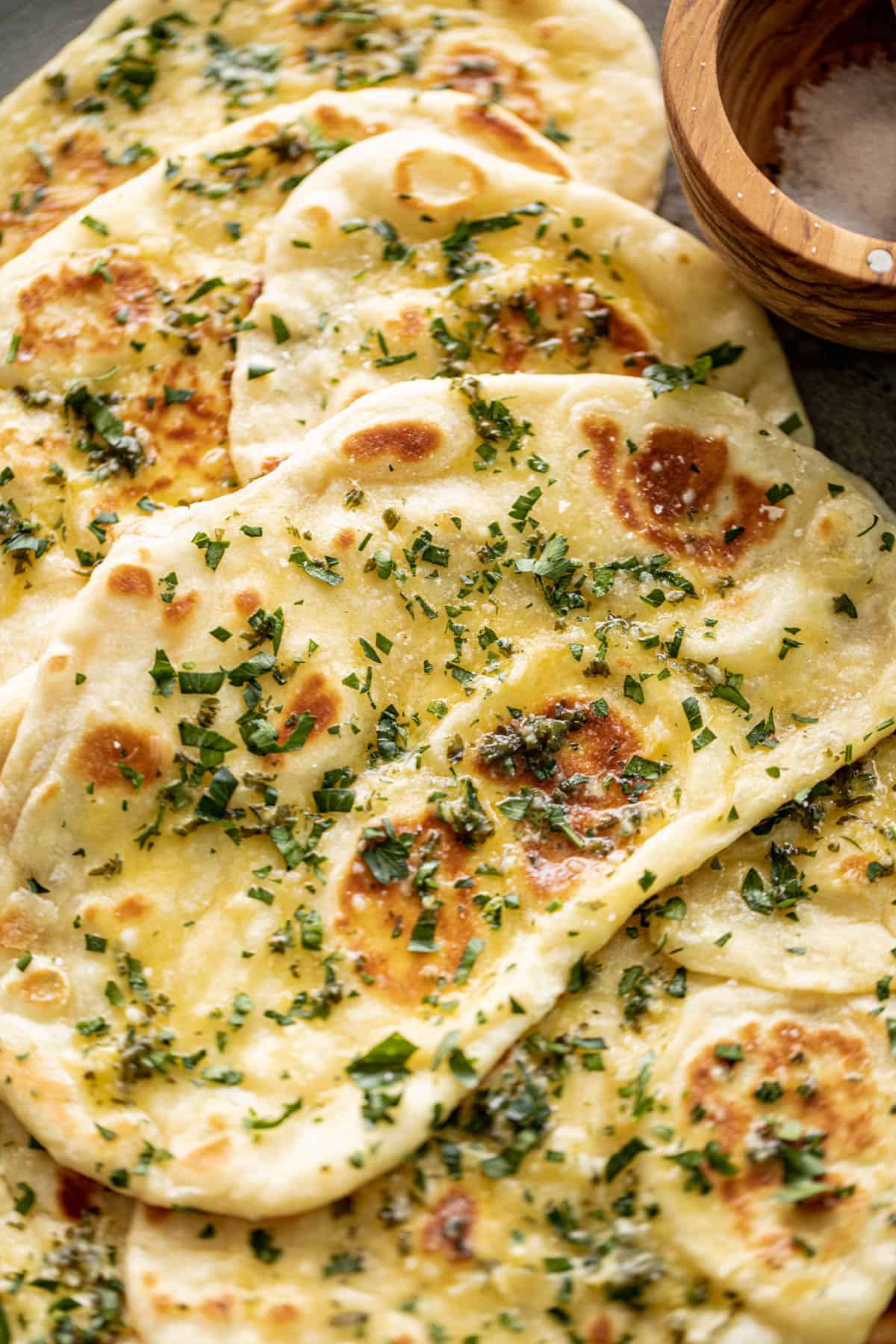 Top view image of Buttery Garlic Naan Breads on a plate with garlic butter and fresh chopped cilantro