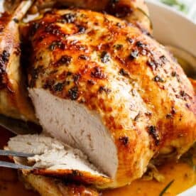 Image of the garlic roast chicken being taken out of the oven and sliced to reveal its tenderness and juiciness.