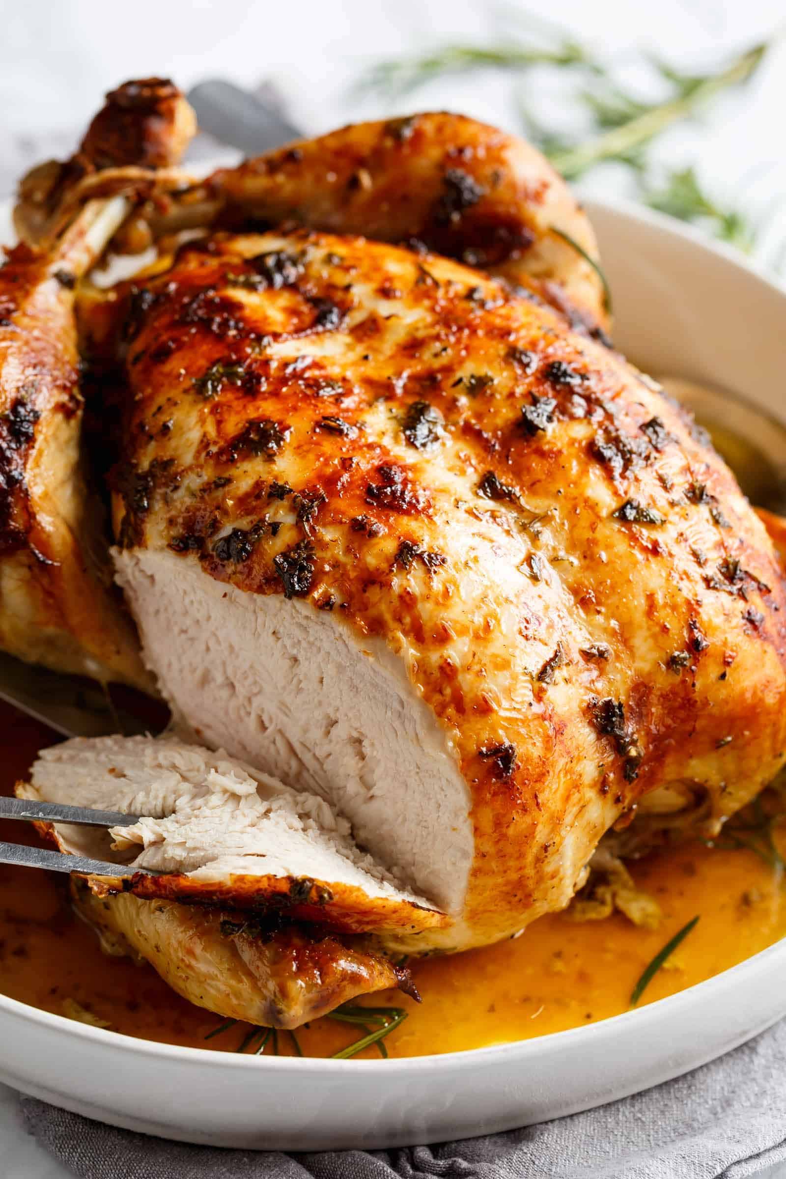 Image of the garlic roast chicken being taken out of the oven and sliced to reveal its tenderness and juiciness.
