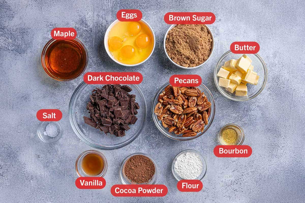 Images of ingredients, specifically maple syrup, eggs, brown sugar, butter, salt, dark chocolate, pecans, vanilla extract, cocoa powder, flour, and bourbon, laid out in clear bowls showcasing the ingredients.
